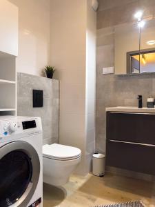 a bathroom with a toilet and a washing machine at Bliżej Morza AON Apartament Gdańsk in Gdańsk