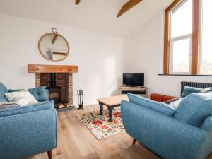a living room with two blue chairs and a fireplace at The Old Workshop in St Austell
