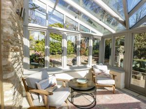 une véranda avec un plafond en verre, des chaises et une table dans l'établissement Rose Cottage, à Corsham