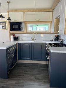 a kitchen with blue cabinets and a sink at Swift Bordeaux 73 in Dunoon