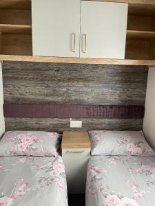 a bedroom with two beds and a wooden wall with a cabinet at Swift Bordeaux 73 in Dunoon