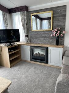 a living room with a fireplace and a television at Swift Bordeaux 73 in Dunoon