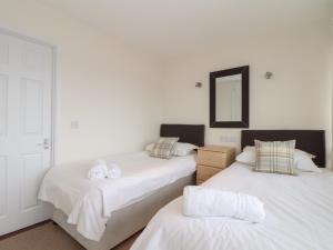um quarto com 2 camas com lençóis brancos e um espelho em 24 Atlantic Reach em Newquay