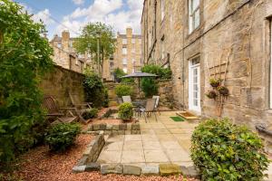 un patio al aire libre con sillas y sombrilla en Elite 3 Bed New Town Apt with Private Walled Garden en Edimburgo