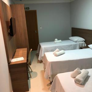 um quarto com três camas com toalhas em KK Palace Hotel em Eunápolis