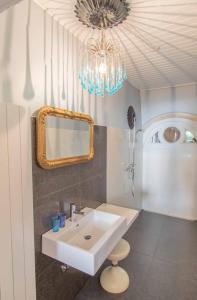 ein Badezimmer mit einem Waschbecken, einem Spiegel und einem Kronleuchter in der Unterkunft Appartement de vacances Un ange passe à Porrentruy in Pruntrut