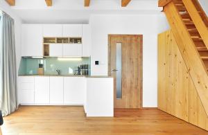 Kvilda Apartments في كفيلدا: مطبخ بدولاب بيضاء وباب خشبي