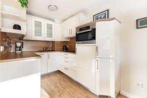 eine Küche mit weißen Schränken und einem Kühlschrank in der Unterkunft Luxus-Loft-Sylt Haus Dünenburg in Westerland
