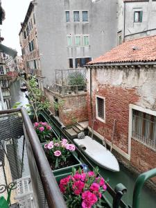 un balcón con un barco en un canal con flores en Casa pergoletto, en Venecia