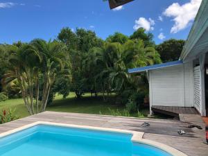 a swimming pool in front of a house with trees at La Case Dentelle in Le Diamant