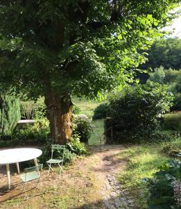 a table and chairs under a tree in a garden at Maison Mercredi in Piégut-Pluviers