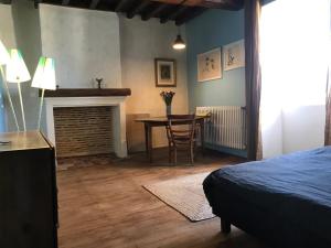 Piégut-PluviersにあるMaison Mercrediのベッドルーム(ベッド1台、テーブル、暖炉付)