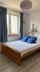 a bedroom with a bed with blue pillows and a window at Pokoje gościnne EWELA in Łeba