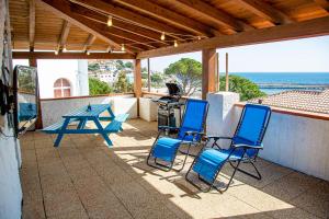 a patio with blue chairs and a picnic table and the ocean at Ti porto al mare Apartment IUN P7641 in Cala Gonone
