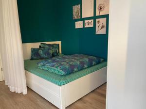ein kleines Bett in einem Zimmer mit grüner Wand in der Unterkunft FEWO "Rabennest " Gemütliche Wohnung nahe Rabensteinklinikum - kein separates Schlafzimmer, Studiowohnung in Chemnitz