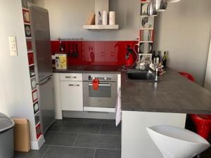 una pequeña cocina con armarios rojos y fregadero en Port Brescou, T3 en duplex climatisé, superbe vue sur le port, en Cap d'Agde