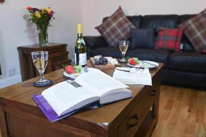 een tafel met een open boek en een fles wijn bij Birchbrae Highland Lodges in Onich