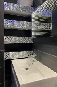 baño con lavabo blanco y azulejos en la pared en La desiroom en Fréjus