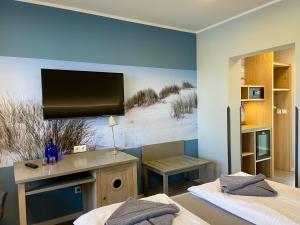 a bedroom with two beds and a tv on the wall at Hotel & Gasthof Zur Linde in Middelhagen