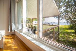 - une fenêtre avec vue sur une terrasse couverte dotée d'une table dans l'établissement Waterfront Edenton Bay Cottage - Walk to Dtwn, à Edenton