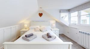 a white bedroom with a large white bed with two pillows at Lobster Cove, 50 yards from the sea in Port Isaac