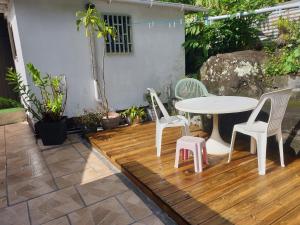 un patio con mesa y sillas en una terraza de madera en case creole en Saint-Joseph