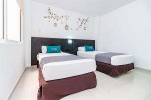 2 camas en una habitación con paredes blancas en Ayenda Quinta Estación, en Yopal