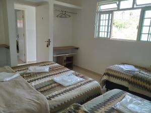 Cette chambre comprend 2 lits et une fenêtre. dans l'établissement POUSADA VILA DO BIRIBIRI, à Diamantina
