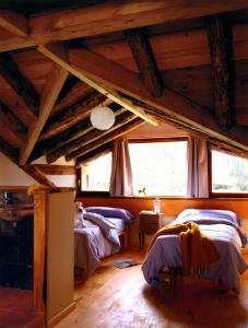 2 Betten in einem Zimmer mit Holzdecken und Fenstern in der Unterkunft Las Casas del Palomar I & II in Ortigosa del Monte