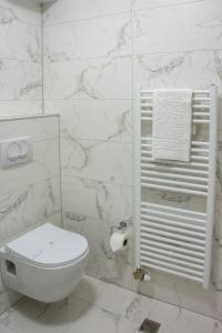 a white bathroom with a toilet and marble walls at Seasons Hotel in Struga