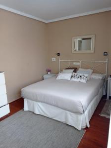 Apartamento Riazor Coruña في لا كورونيا: غرفة نوم بسرير ابيض كبير ومرآة