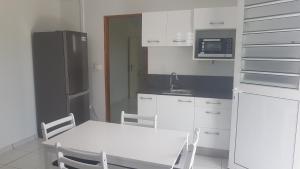 a kitchen with a white table and a refrigerator at T2 en résidence chez l'habitant in Ducos