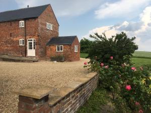 an old brick house with a brick wall and flowers at Cosy getaway near Rutland Water in Oakham