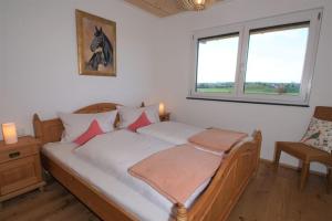 une chambre avec un lit avec des draps blancs et des oreillers roses dans l'établissement Linda‘s Ferien-Pferdehof, à Sigmarszell