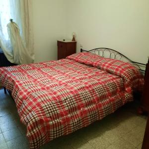Una cama con una manta roja y blanca de cuadros. en NONNA MARI, en Montepulciano