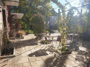 a patio with tables and chairs in a garden at Hôtel Saint Cyr in La Ferté-Saint-Cyr