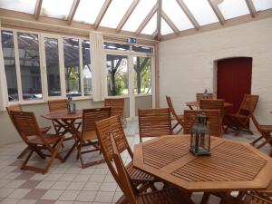 Harboøre Hotel في هاربور: مطعم بطاولات وكراسي خشبية ونوافذ