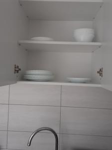 a kitchen with white cabinets and a sink and plates at Sara apartman in Livezeni +24 photos