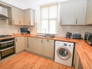 a kitchen with white cabinets and a washing machine at Gwel Y Castell Castle View in Criccieth