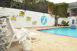 a swimming pool with two chairs next to a white wall at Zarabanda Campestre - Moderna Casa Campestre para alojamiento y eventos in Tuluá
