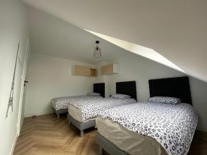two beds in a room with white walls at Les Rives Saint Symphorien, appartements meublés in Longeville-lès-Metz