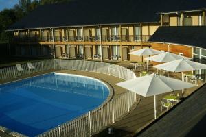埃屈埃莫維爾的住宿－阿多尼斯酒店，一个带遮阳伞和桌子的游泳池以及一座建筑