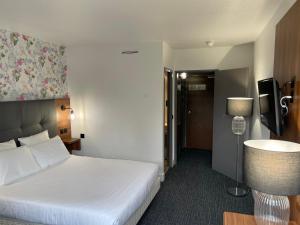 une chambre d'hôtel avec un lit blanc et une lampe dans l'établissement Hôtel Akena Poitiers Nord Futuroscope, à Chasseneuil-du-Poitou