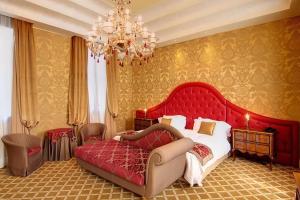 a bedroom with a large red bed and a chandelier at Pesaro Palace in Venice