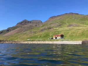 uma casa numa praia ao lado de uma montanha em Bergistangi Guest House em Norðurfjörður