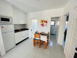 een keuken met een tafel en een keuken met witte apparatuur bij Aguazul - A pie de piscina y vistas al mar in Puerto del Carmen