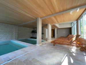 a swimming pool with a bench next to a house at Apto 2 Dorms, 1 Suíte, JP2 Home Resort Ubatuba - Churrasqueira Gourmet, Ar Condicionado, Piscinas, Sauna e Salão de Jogos in Ubatuba