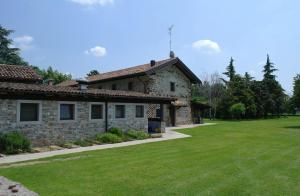 a stone house with a green lawn in front of it at Agriturismo il Vagabondo in Buttrio