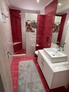 bagno con lavandino, servizi igienici e piastrelle rosse di EVA'S HOME a Kefalos