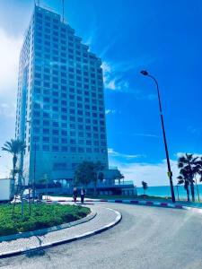 um edifício alto com uma estrada em frente ao oceano em מלון כרמל/מגדל C em Netanya
